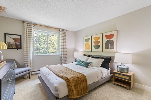 A bedroom with a large bed and a window with curtains.