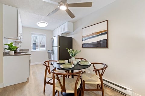 A dining room with a table set for two and a ceiling fan.