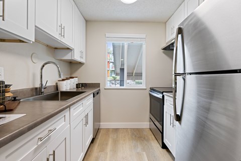 A kitchen with a stainless steel refrigerator and white cabinets.