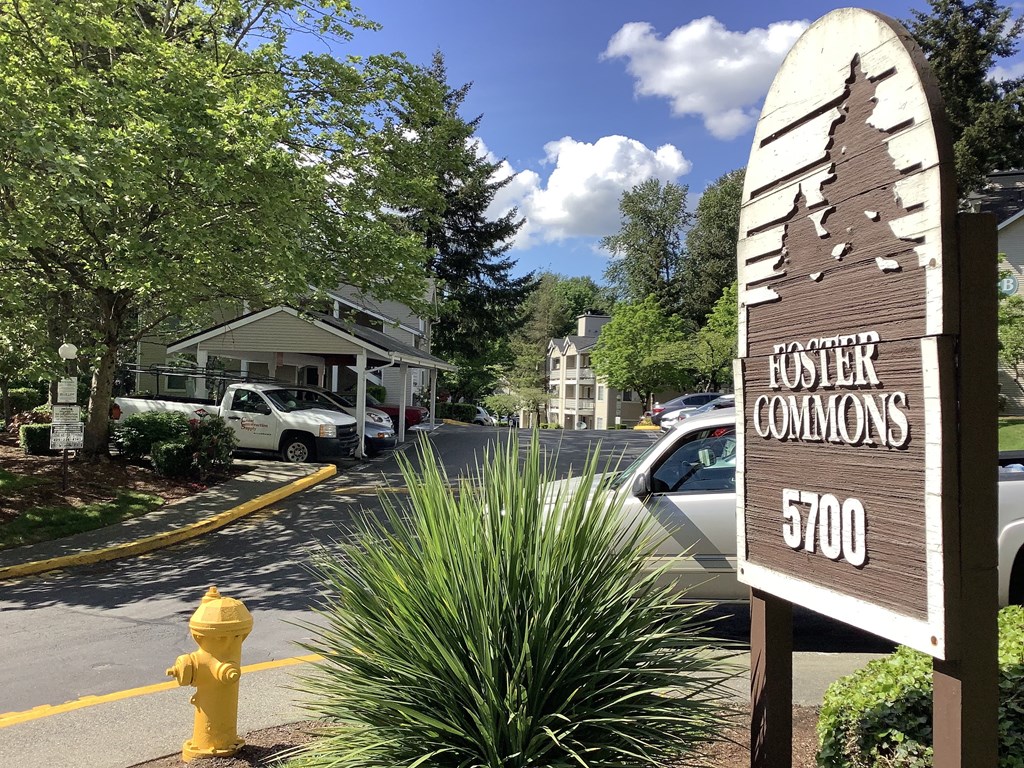 A yellow fire hydrant is in front of a sign for Hoster Commons.