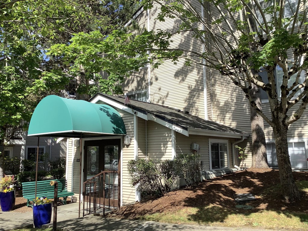 A house with a green awning and a tree in front.