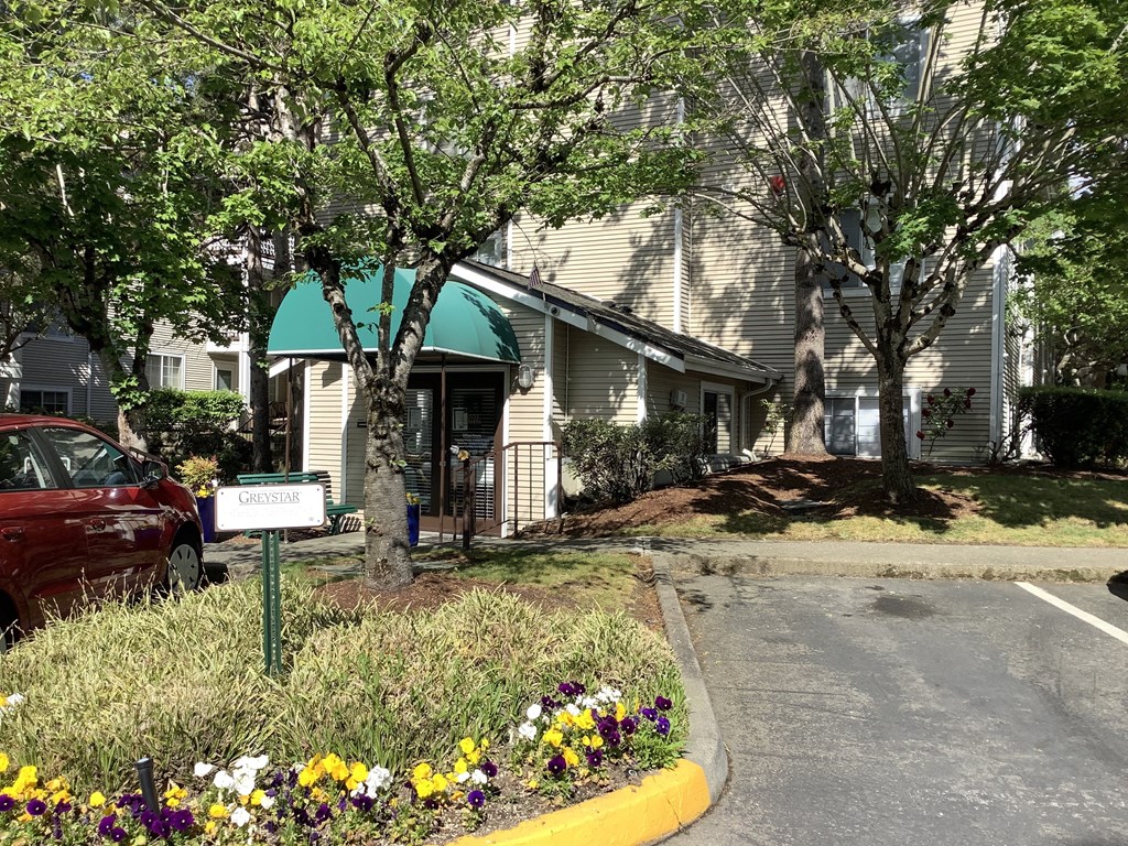 A red car is parked in front of a house with a green roof and a sign that says "Ludlow".