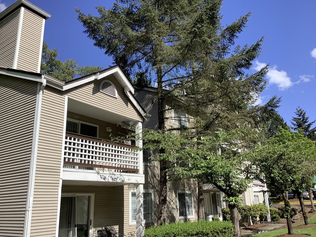 A house with a balcony and a tree in front.