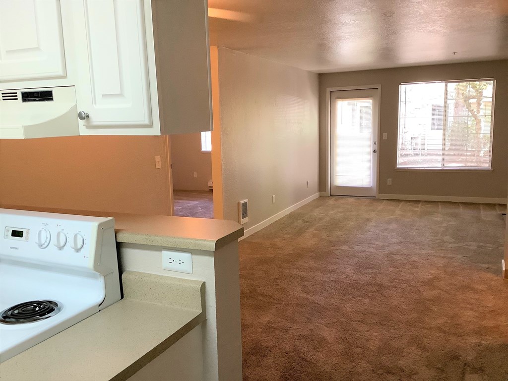 A kitchen with a white stove and white cabinets.