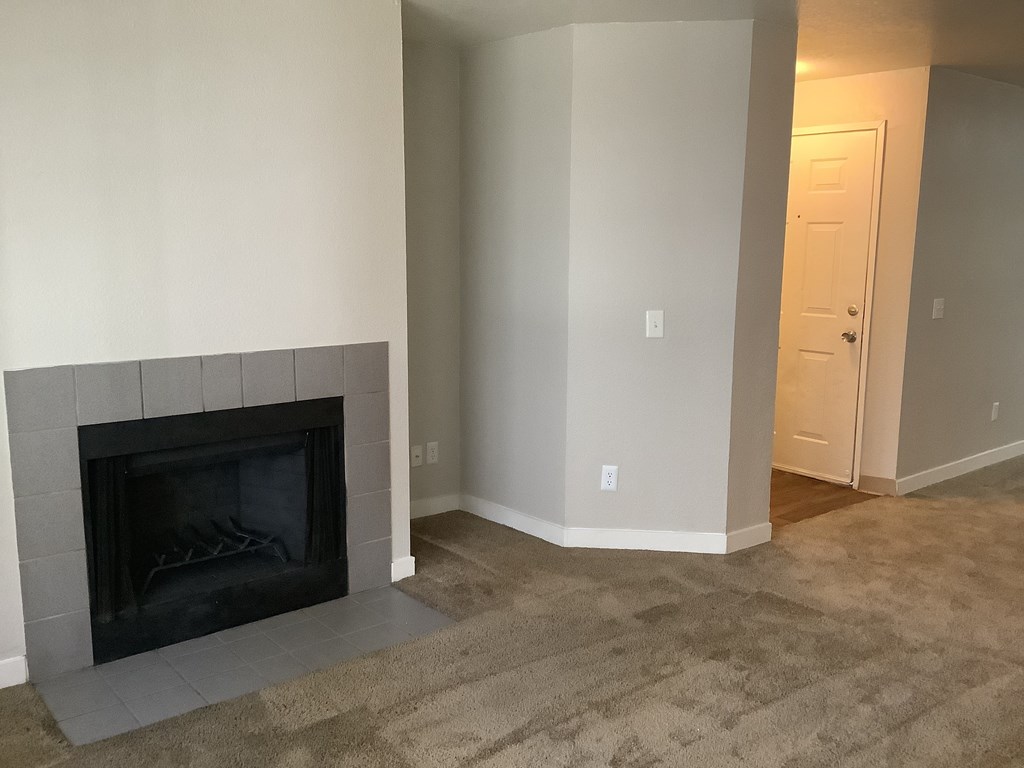 A black fireplace in a room with a carpeted floor.