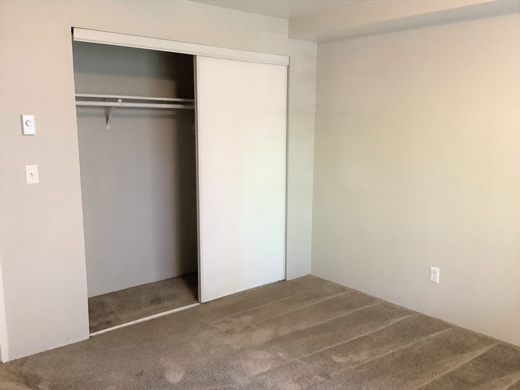 A room with a white door and a carpeted floor.
