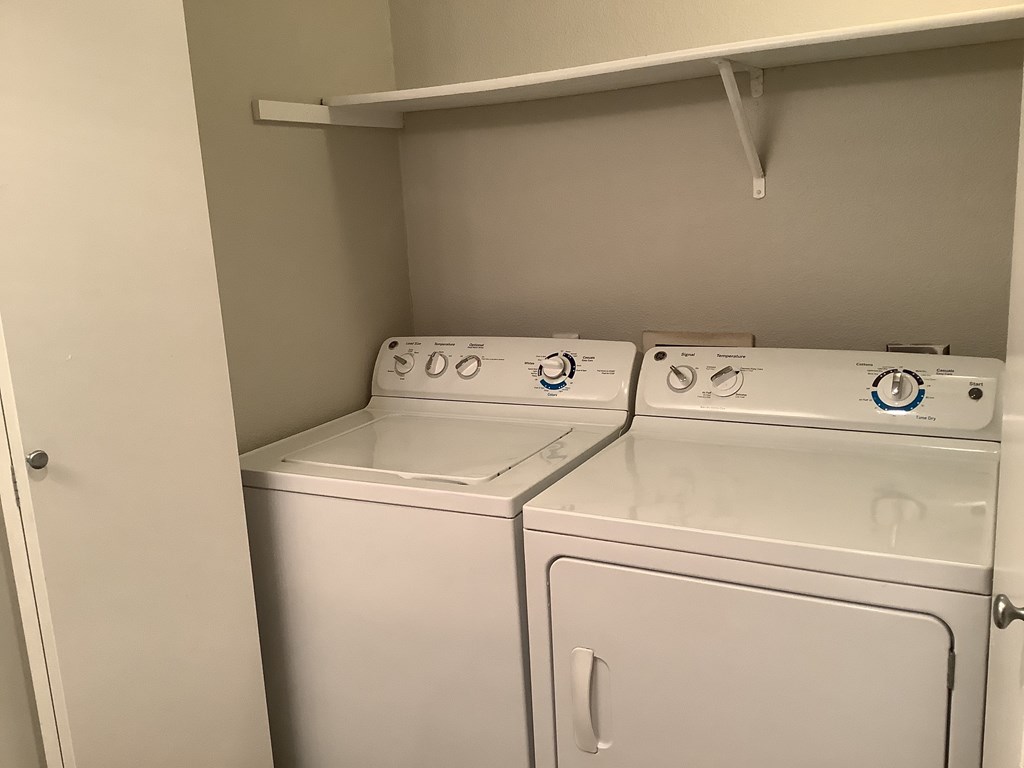 Two white washing machines in a small laundry room.