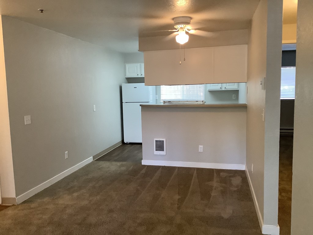 A kitchen area with a refrigerator, cabinets, and a ceiling fan.