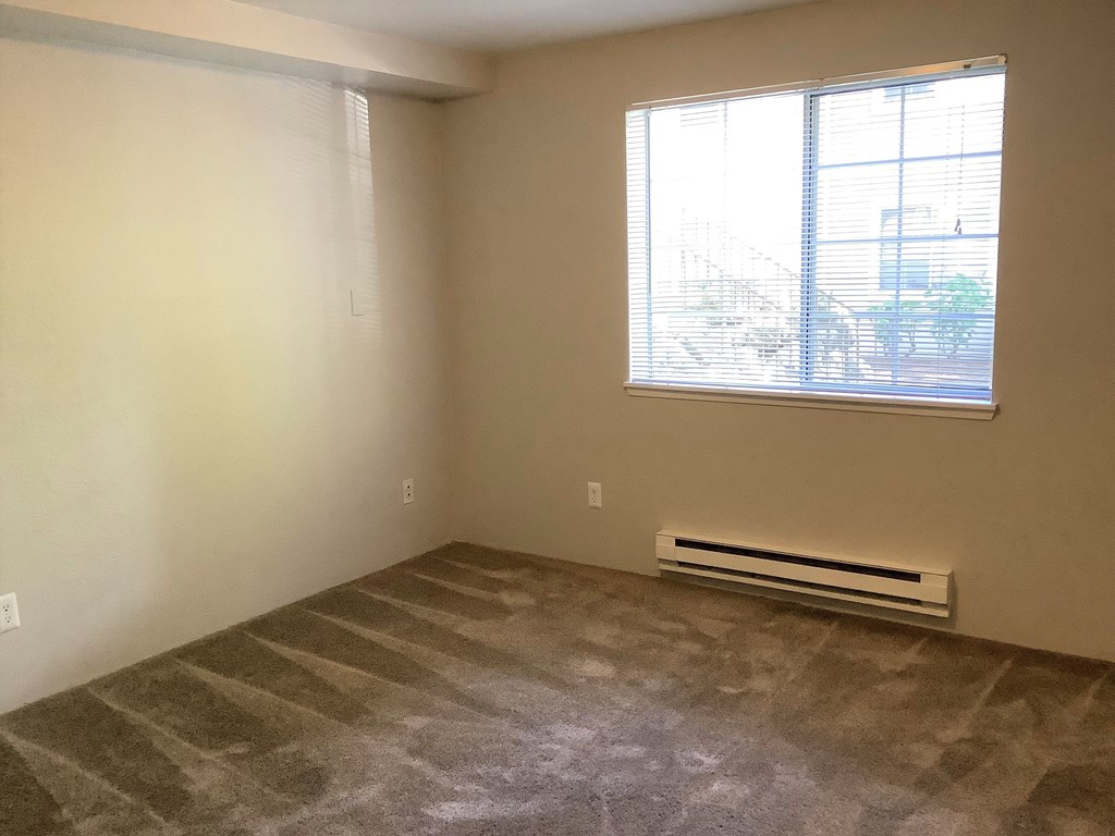 A room with a window and a heater on the floor.