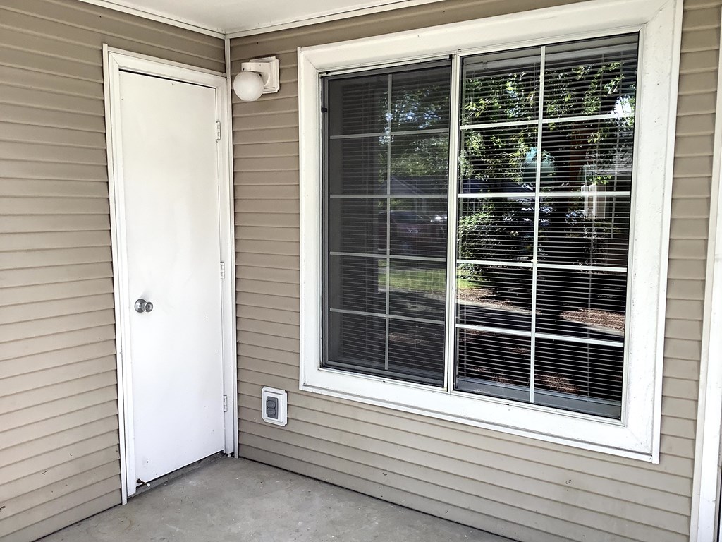 A white door is on the left and a window with blinds is on the right.