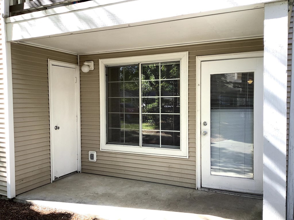 A small house with a white door and a window with blinds.