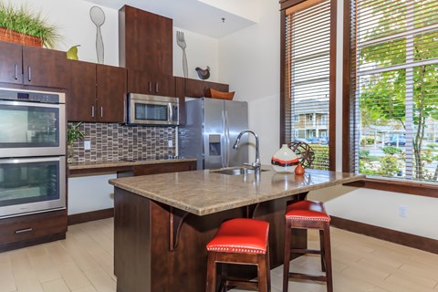 A kitchen with a brown counter top and red bar stools.