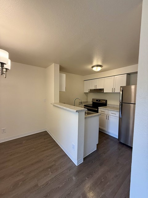 A kitchen with white cabinets and a stainless steel refrigerator.