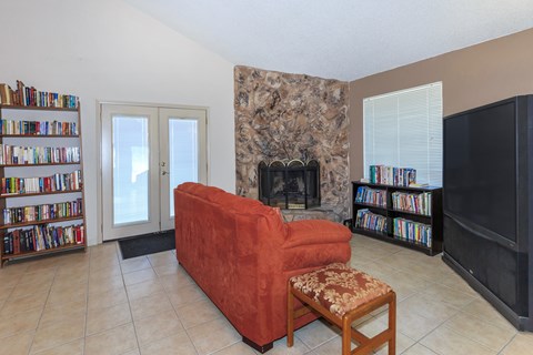 A living room with a red couch, a fireplace, and a bookshelf.