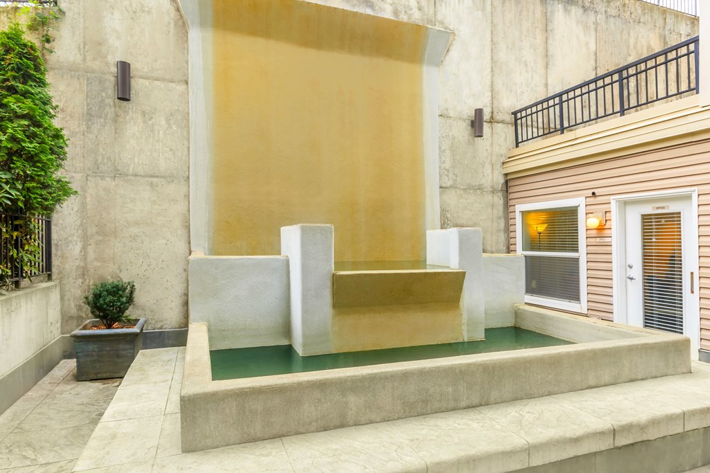 A modern house with a yellow wall and a small pool in front.