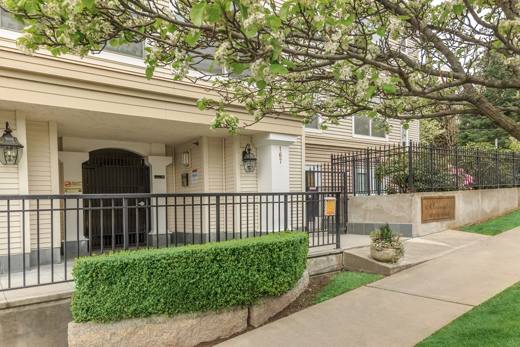 A house with a black gate and a green hedge in front.