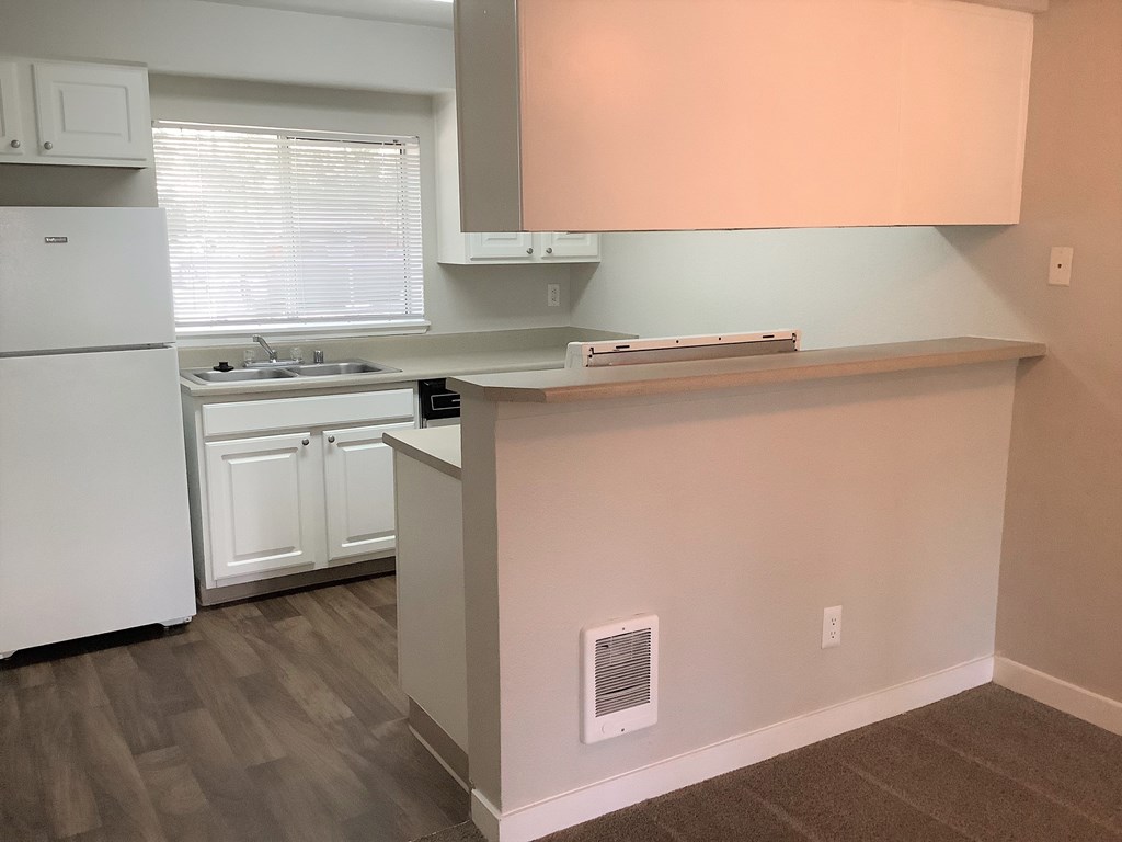 A kitchen with white appliances and a window.