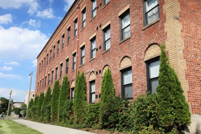 A red brick building with green trees in front.