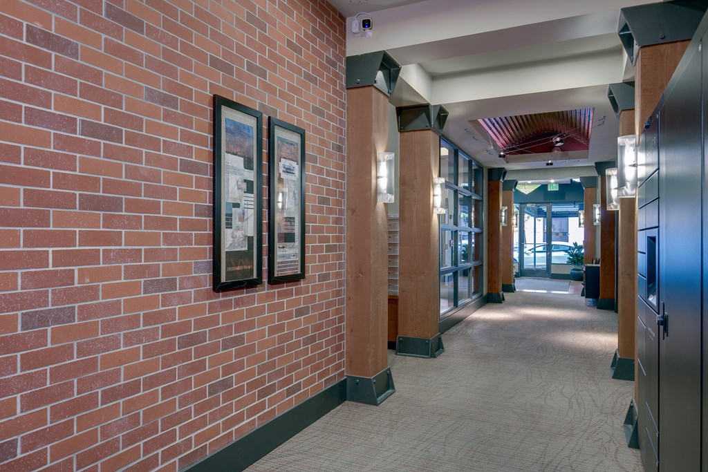 A hallway with a brick wall and framed pictures on it.