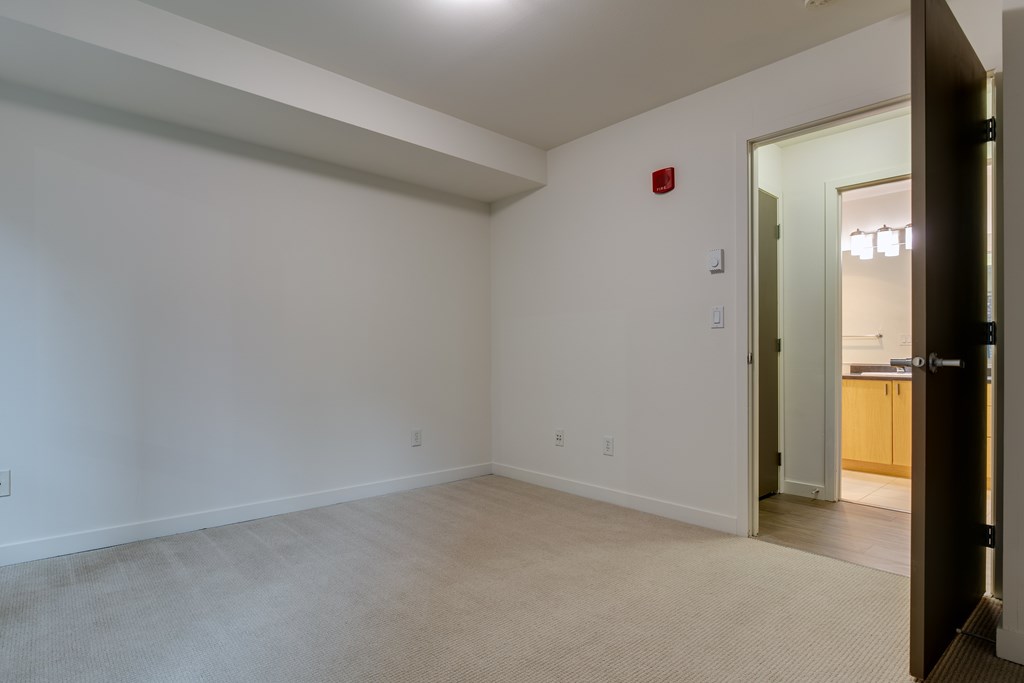 A room with a white wall and a red fire alarm.
