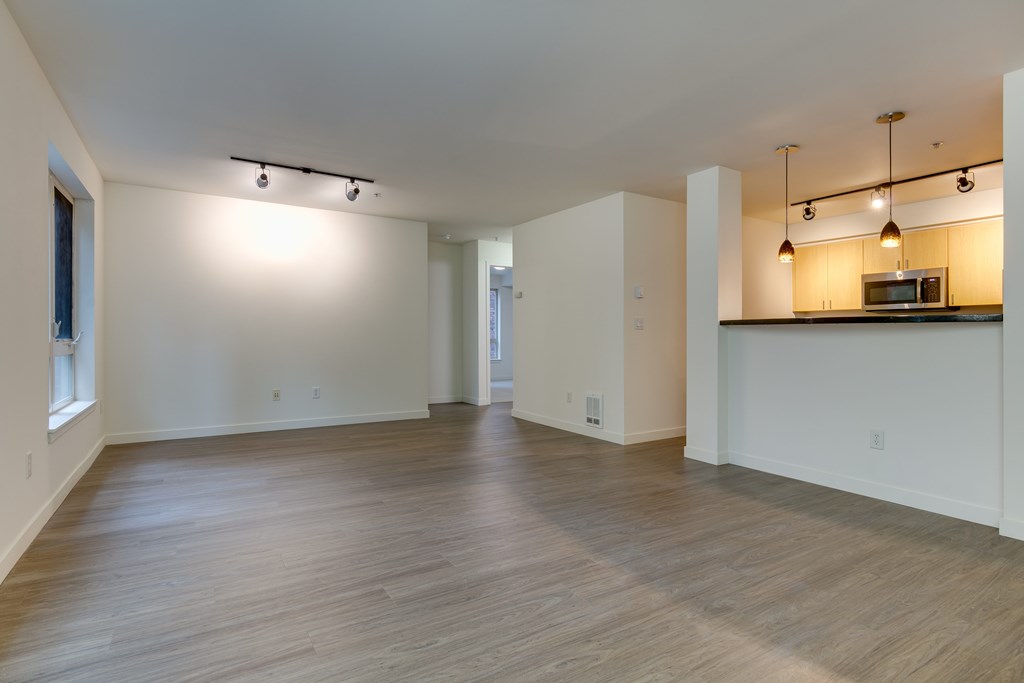 A spacious room with wooden floors and a bar area with a microwave.