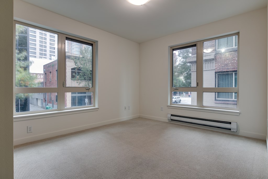 A spacious room with two windows overlooking a cityscape.
