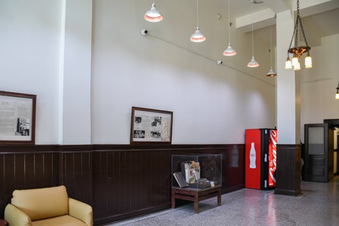 A yellow chair sits in front of a wooden wall with a framed picture on it.