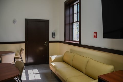 A yellow couch sits in a room with a brown door.