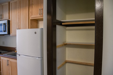 A white refrigerator stands in a kitchen next to a wall.