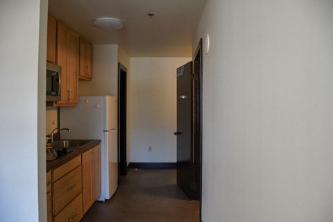 A kitchen with a sink, refrigerator, and cabinets.