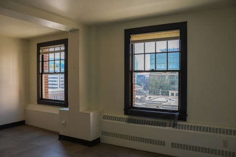 Two windows in a room with a view of the city.