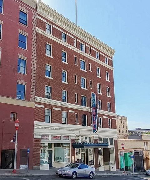 A tall red brick building with a sign that says "HOTEL" on the front.