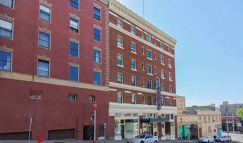A red brick building with a blue awning sits on a street corner.