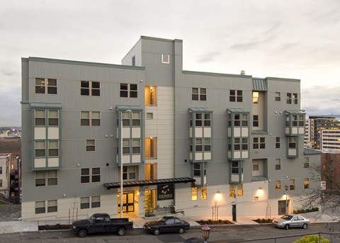 A grey building with a black truck parked in front.