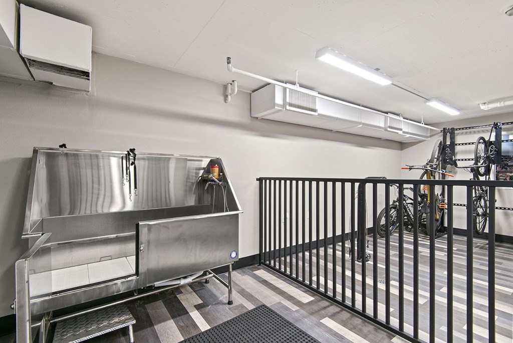 A large stainless steel sink in a room with a black fence.