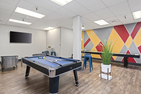 A pool table in a room with a TV mounted on the wall.