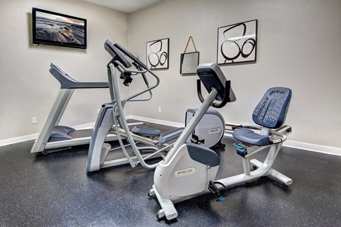 A gym room with a rowing machine and a stationary bike.