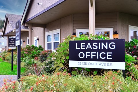 A leasing office sign is in front of a building.