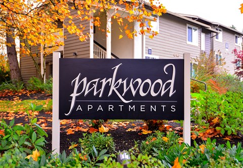 A sign for Parkwood Apartments is in front of a building.