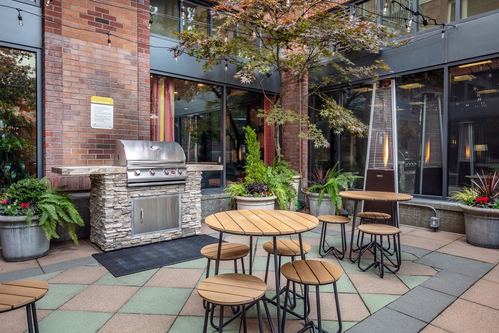 A patio with a table and chairs and a grill.