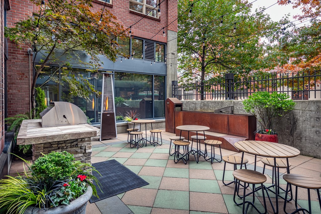 A patio with tables and chairs is surrounded by trees.