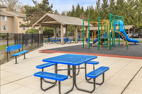 A playground with a blue picnic table and yellow slide.