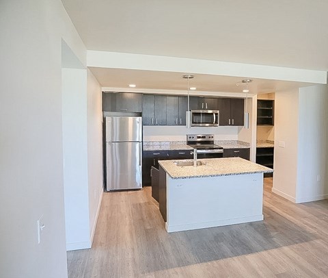 A modern kitchen with a stainless steel refrigerator and a granite countertop.
