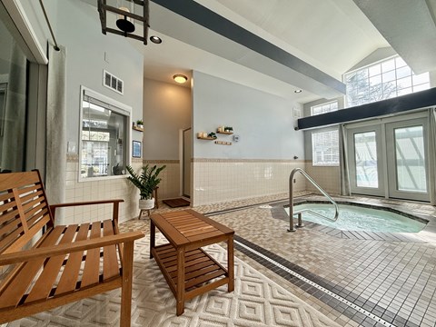 A wooden chair and table are placed in a room with a hot tub.