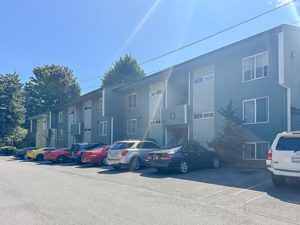 A sunny day at the apartment complex with cars parked in front.