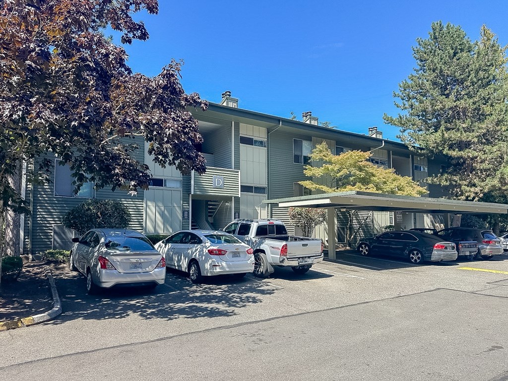 Cars parked in front of a building with a tree on the right.