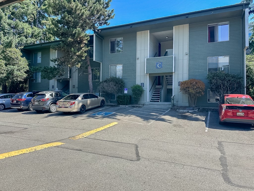 A parking lot in front of a building with cars parked.