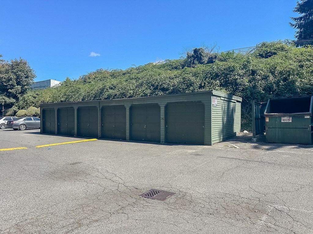 A parking lot with a row of green garages and a car parked in the background.
