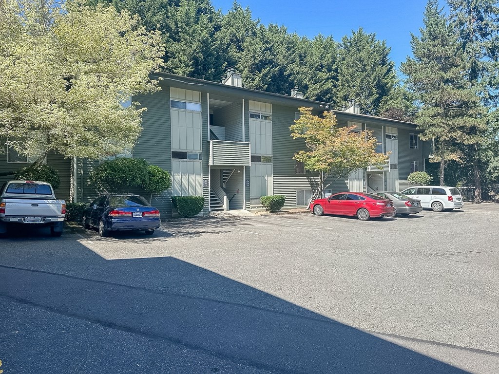 A parking lot in front of a building with cars parked.