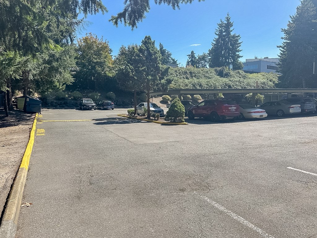 A parking lot with cars parked and trees in the background.